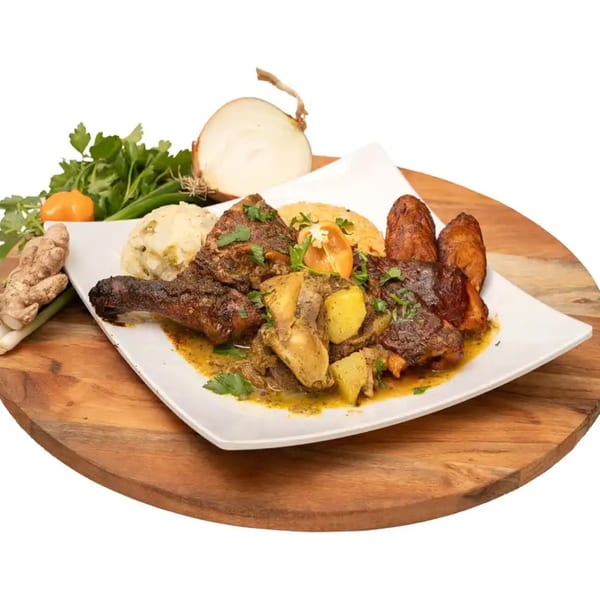 A Caribbean meal with stewed chicken, potatoes, rice, mashed provisions, and fried plantains on a white plate.